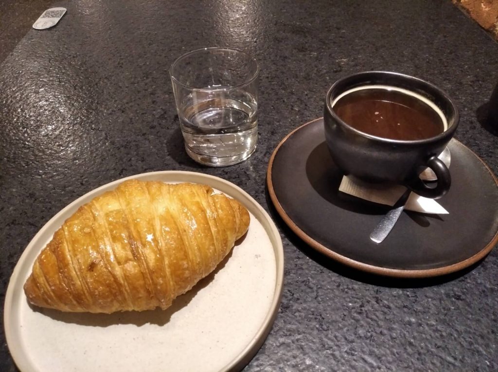 Tasse de café accompagnée d'un verre d'eau gazeuse et d'un croissant (medialuna) dans un bar en Argentine