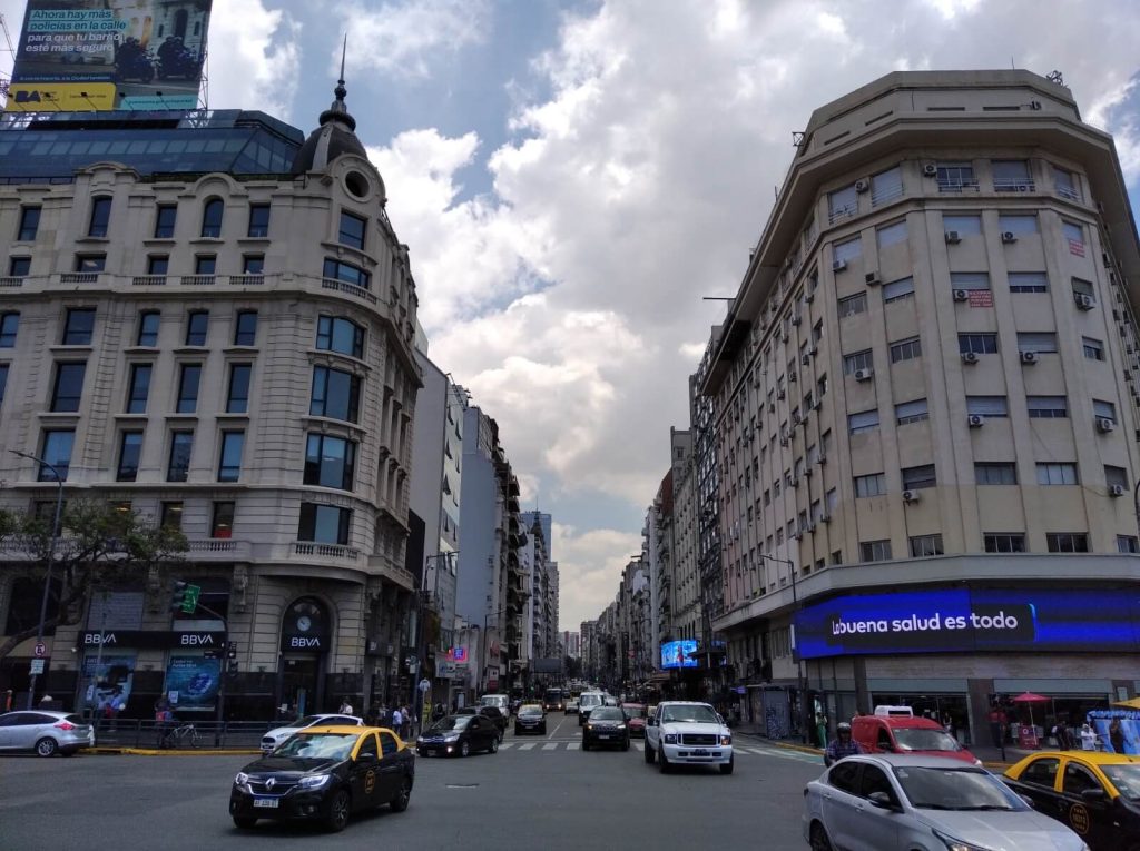 3 taxis, au milieu d'autres voitures, franchissent l'intersection des avenues Corrientes et 9 de Julio à Buenos Aires