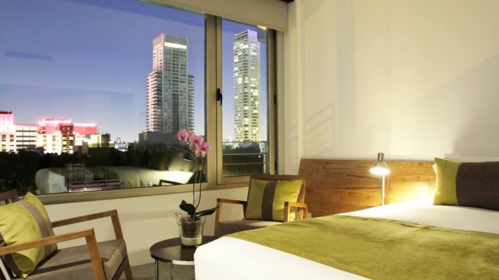 Lit matrimonial et vue sur les buildings du quartier de Palermo dans une chambre de Palo Santo Hotel à Buenos Aires